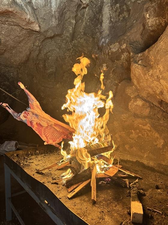 Chivito neuquino al asador junto al fuego en la caverna