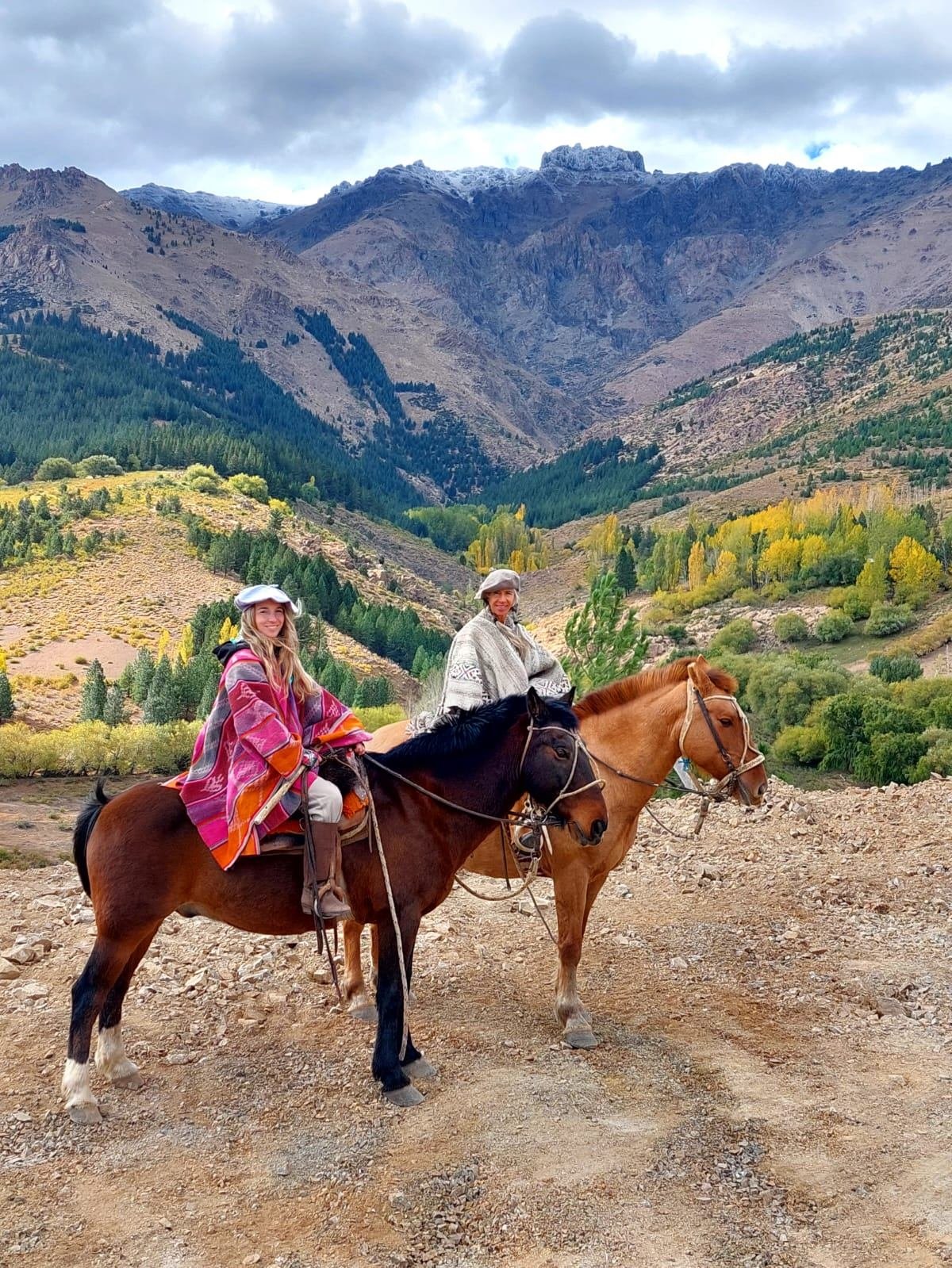 Jinetes en la Cordillera del Viento con picos nevados de fondo